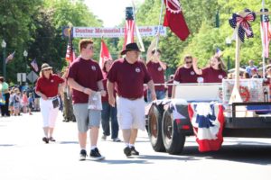 student and mentor walk beside parade float