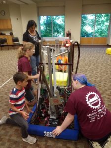 a couple young kids looking at our robot